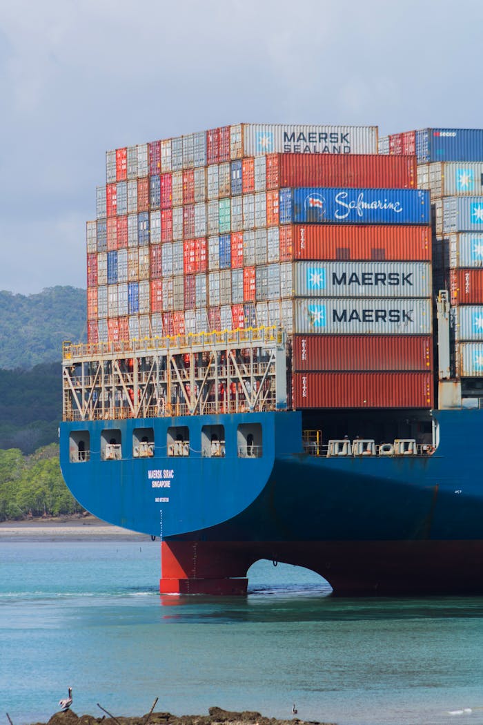 A cargo ship loaded with containers navigates the Panama Canal under clear skies.